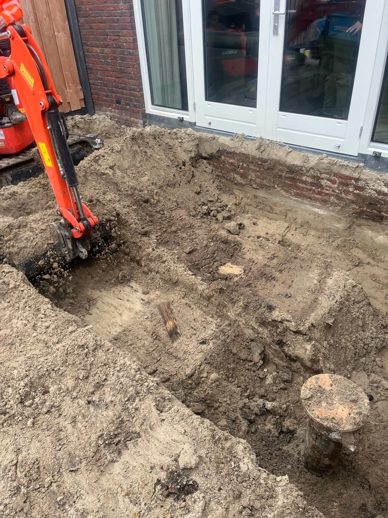 Minigraver graaft de fundering uit achter een woning