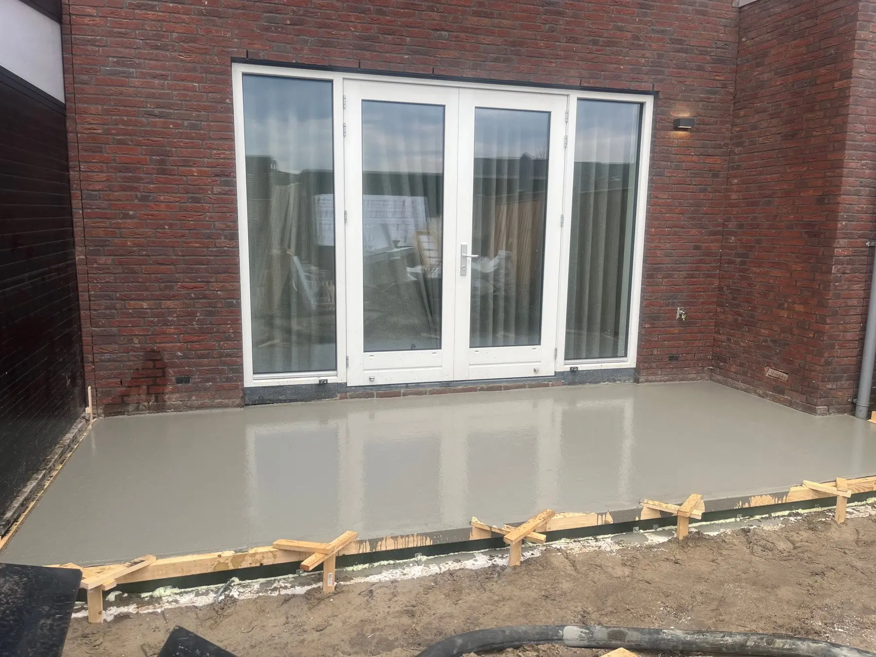 Vers gestorte en vlak afgewerkte betonvloer achter een woning